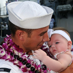 US Navy man hugs newborn daughter for the first time.